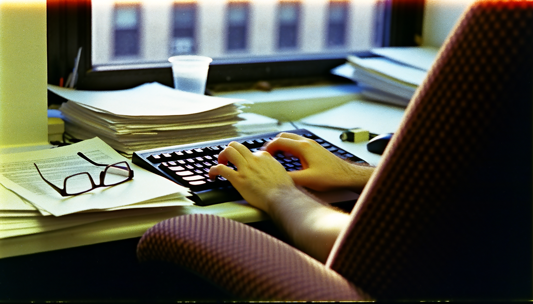 Person typing on a keyboard, illuminated desk with documents and laptop screen, showcasing Web3 trends.